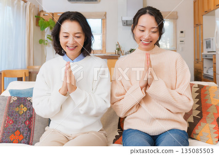 Mother and daughter eating together with hands together 135085503