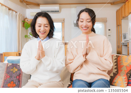 Mother and daughter eating together with hands together 135085504