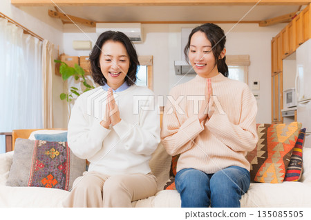 Mother and daughter eating together with hands together 135085505