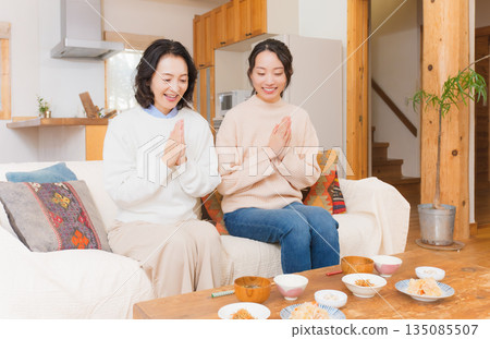 Mother and daughter eating together with hands together 135085507