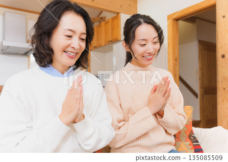 Mother and daughter eating together with hands together 135085509