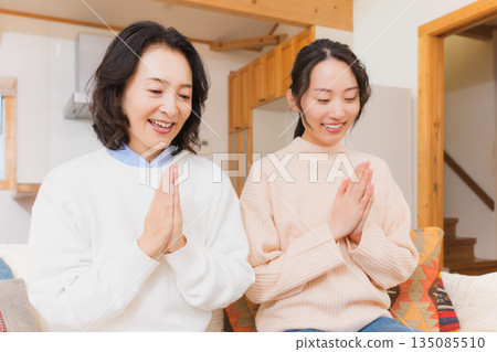 Mother and daughter eating together with hands together 135085510