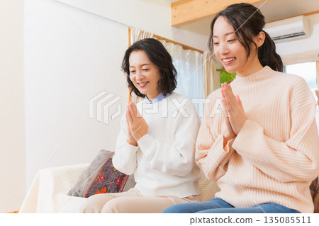 Mother and daughter eating together with hands together 135085511