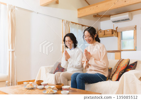 Mother and daughter eating together with hands together 135085512