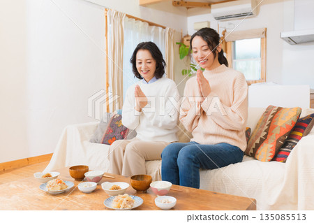 Mother and daughter eating together with hands together 135085513