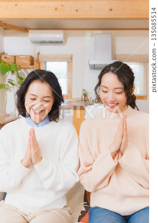 Mother and daughter eating together with hands together 135085514