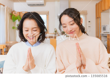 Mother and daughter eating together with hands together 135085516