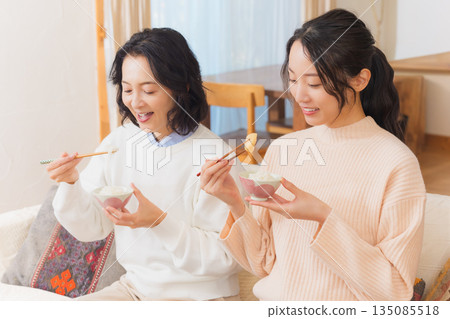 Mother and daughter eating together with hands together 135085518