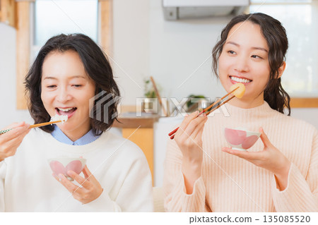 Mother and daughter eating together with hands together 135085520