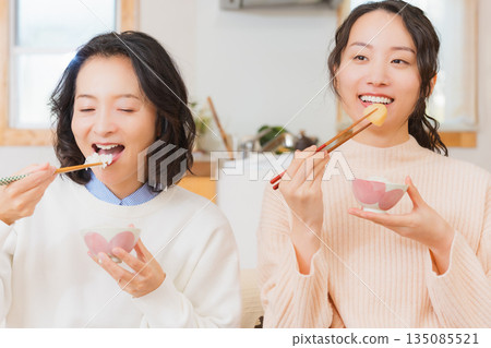 Mother and daughter eating together with hands together 135085521