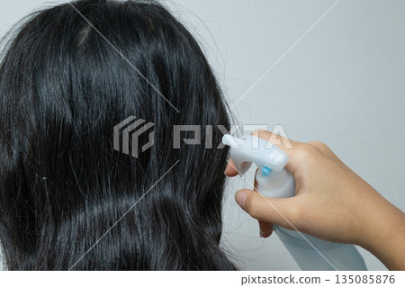 一個孩子從後面往頭髮上噴髮膠 135085876