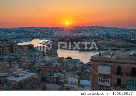 A stunning aerial view of Valletta's rooftops, showcasing the city's historic architecture, domes, and limestone buildings under the Mediterranean sky. A stunning aerial view of Valletta's rooftops, showcasing the city's historic architecture, domes, and limestone buildings under the Mediterranean sky. 135086037