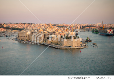 A stunning panoramic view of Birgu Port as seen from a Valletta vantage point, showcasing historic architecture, docked boats, and the scenic Maltese coastline. A stunning panoramic view of Birgu Port as seen from a Valletta vantage point, showcasing historic architecture, docked boats, and the scenic Maltese coastline. 135086049