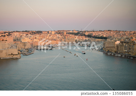 A stunning panoramic view of Birgu Port as seen from a Valletta vantage point, showcasing historic architecture, docked boats, and the scenic Maltese coastline. A stunning panoramic view of Birgu Port as seen from a Valletta vantage point, showcasing historic architecture, docked boats, and the scenic Maltese coastline. 135086055