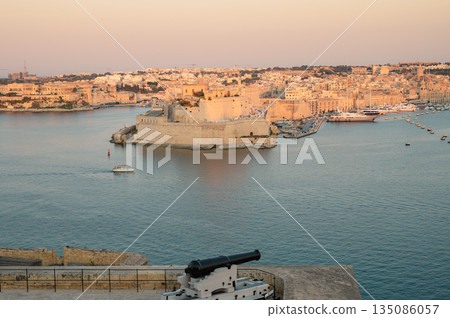 A stunning panoramic view of Birgu Port as seen from a Valletta vantage point, showcasing historic architecture, docked boats, and the scenic Maltese coastline. 135086057