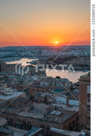 A stunning aerial view of Valletta's rooftops, showcasing the city's historic architecture, domes, and limestone buildings under the Mediterranean sky. 135086058