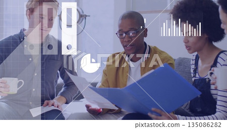 Reviewing documents from blue folder, team sitting on gray sofa in modern office lounge, with mugs 135086282