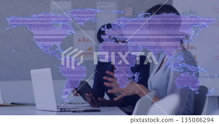 Analyzing business colleagues reviewing data at meeting table, with laptop, holographic map overlay 135086294