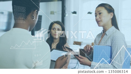 Discussing data three women holding digital tablets and blue folder in office, projecting holograms Discussing data three women holding digital tablets and blue folder in office, projecting holograms 135086314