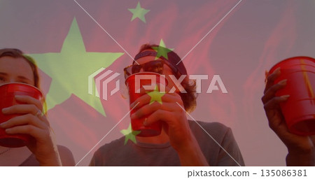 Sipping friends wearing baseball cap and sunglasses at sunset gathering, with red plastic cups 135086381