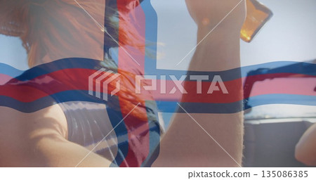 Clinking beer bottles red-haired woman and friend on boat deck at sea with flag overlay 135086385