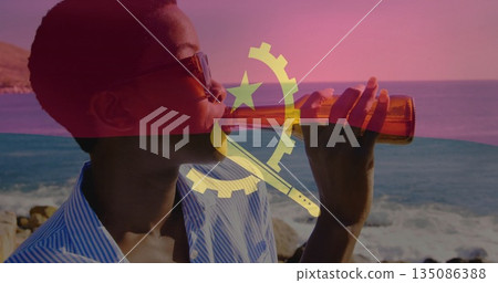 Sipping African American woman with bottle by rocky coast wearing sunglasses showing Angola flag Sipping African American woman with bottle by rocky coast wearing sunglasses showing Angola flag 135086388