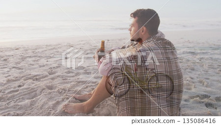 Sitting man wearing plaid shirt, holding bottle at sandy beach with bicycle silhouette copy space Sitting man wearing plaid shirt, holding bottle at sandy beach with bicycle silhouette copy space 135086416