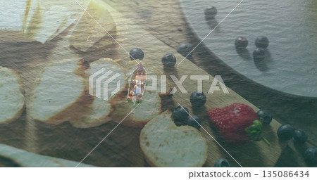Men in rowboat rowing on calm lake, with cutting board holding bread slices blueberries strawberry Men in rowboat rowing on calm lake, with cutting board holding bread slices blueberries strawberry 135086434