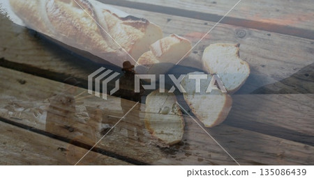 Featuring sliced French baguette loaf on wooden plank at workshop, coat and hat silhouette Featuring sliced French baguette loaf on wooden plank at workshop, coat and hat silhouette 135086439