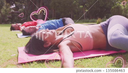 Lying woman in sports bra, leggings stretching arms out on grassy park lawn, with yoga mats Lying woman in sports bra, leggings stretching arms out on grassy park lawn, with yoga mats 135086463