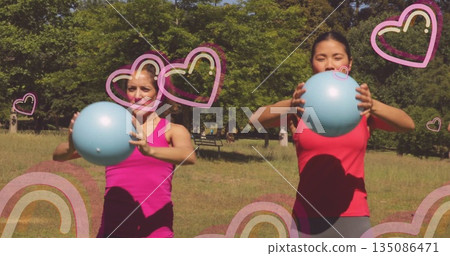 Friends in red, magenta tops exercising with blue balls in sunny park, with heart rainbow overlays Friends in red, magenta tops exercising with blue balls in sunny park, with heart rainbow overlays 135086471