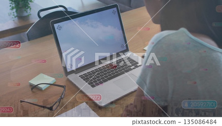 Typing woman in grey T-shirt at office table with data overlays and notes, copy space Typing woman in grey T-shirt at office table with data overlays and notes, copy space 135086484