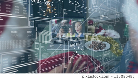 Manipulating gloved Santa hand touching holographic charts on family call at home desk with cookies 135086495