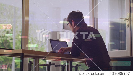 Typing mature Asian man bespectacled working at home office, with laptop and data overlay 135086507