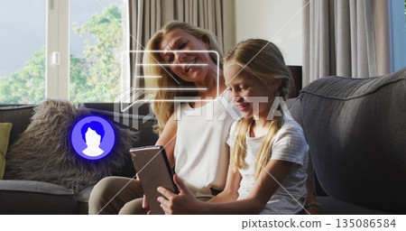 Watching grandmother and granddaughter browsing tablet in living room on sofa with digital overlays Watching grandmother and granddaughter browsing tablet in living room on sofa with digital overlays 135086584
