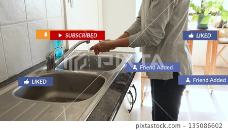 Woman washing hands under faucet in kitchen, with blue soap dispenser and notifications, copy space Woman washing hands under faucet in kitchen, with blue soap dispenser and notifications, copy space 135086602