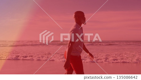 Man walking along sandy beach with foamy ocean waves, wearing white polo shirt, red athletic shorts Man walking along sandy beach with foamy ocean waves, wearing white polo shirt, red athletic shorts 135086642