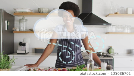 Standing woman in apron chopping vegetables on kitchen counter, with olive oil and cloud overlay 135086701