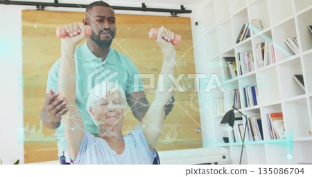 Male caregiver guiding senior woman in wheelchair lifting pink dumbbells in therapy, data overlay 135086704