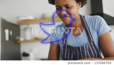 Chopping vegetables woman wearing striped apron at kitchen counter, with neon bird overlay 135086708