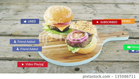 Featuring gourmet hamburgers on sesame buns atop cutting board on wooden table, with notifications Featuring gourmet hamburgers on sesame buns atop cutting board on wooden table, with notifications 135086711