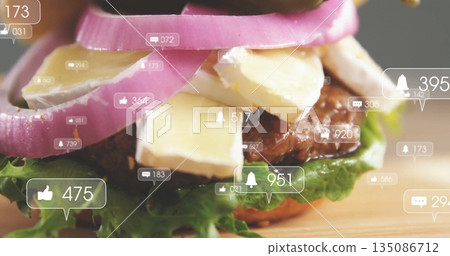 Showing beef burger layering lettuce cheese pickled onion rings on board with social reaction icons 135086712