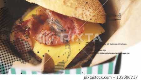 Resting bacon cheeseburger revealing melted cheese and bacon strips at cafe, in green-and-white box 135086717