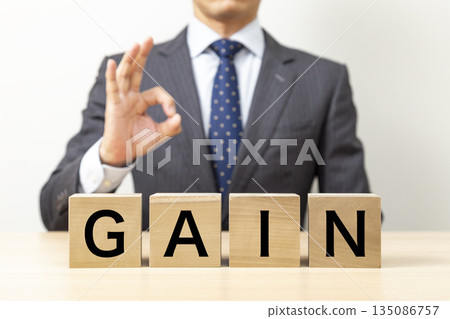 A businessman making an OK pose with a block that says "GAIN" A businessman making an OK pose with a block that says "GAIN" 135086757