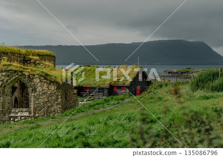 Charming Faroese Village Scene with Grass-Roof Cottages in Kirkjubour, Faroe Islands. High quality photo Charming Faroese Village Scene with Grass-Roof Cottages in Kirkjubour, Faroe Islands. High quality photo 135086796