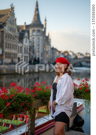 Elegant, well-groomed woman with fashionable style strolling around the city in a white shirt, little black dress and sunglasses. Looking confident and sophisticated. 135086860