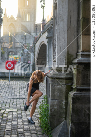 Elegant, well-groomed woman with fashionable style strolling around the city at early morning in a little black dress and sunglasses. Looking confident and sophisticated. 135086862