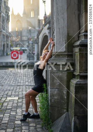 Elegant, well-groomed woman with fashionable style strolling around the city at early morning in a little black dress and sunglasses. Looking confident and sophisticated. 135086924