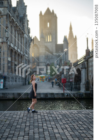 Elegant, well-groomed woman with fashionable style strolling around the city at early morning in a little black dress and sunglasses. Looking confident and sophisticated. Elegant, well-groomed woman with fashionable style strolling around the city at early morning in a little black dress and sunglasses. Looking confident and sophisticated. 135087008
