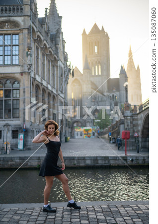 Elegant, well-groomed woman with fashionable style strolling around the city at early morning in a little black dress and sunglasses. Looking confident and sophisticated. 135087060